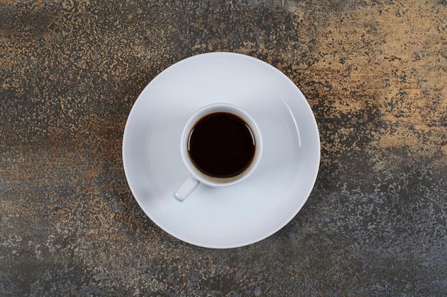 Чашка черного кофе на мраморной поверхности.