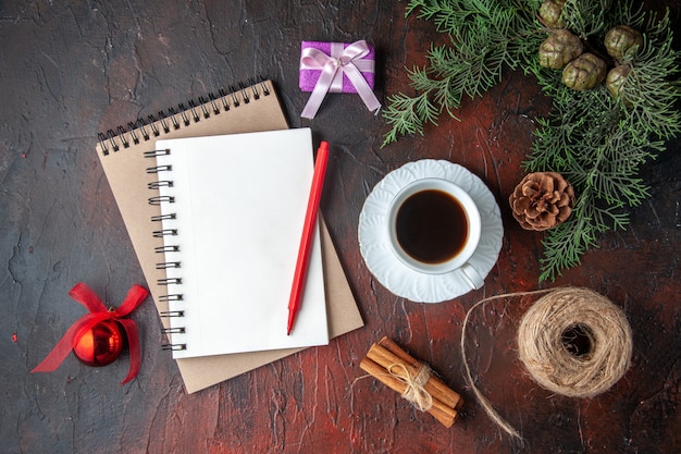 A cup of black tea fir branches decoration accessories and gift and notebook with pen on dark background