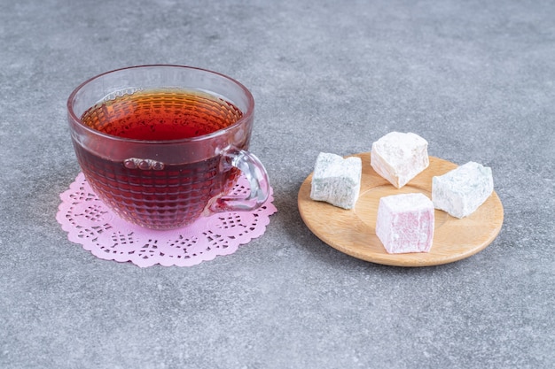Tazza di tè nero e caramelle morbide sulla superficie di marmo