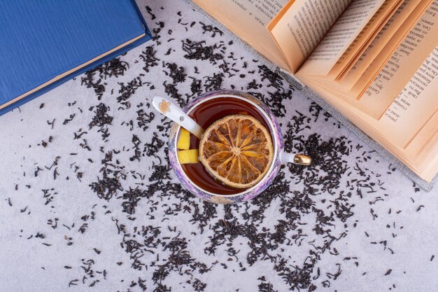 Cup of black tea with fruit slices and books. High quality photo
