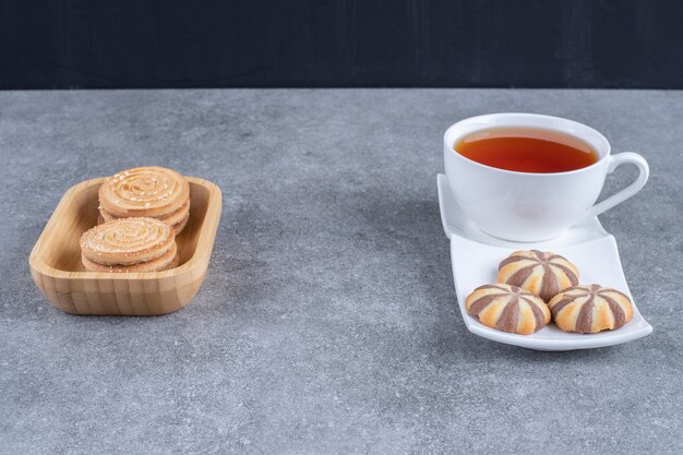 Cup of black tea with various biscuits on marble surfacek