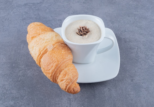 Cup of cappuccino and croissant for breakfast on grey background. Free Photo