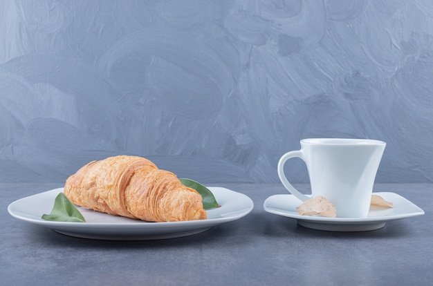 Cup of Cappuccino and croissant for breakfast on grey background.