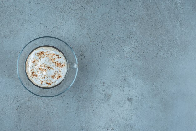 A cup of cappuccino on a saucer , on the blue background.