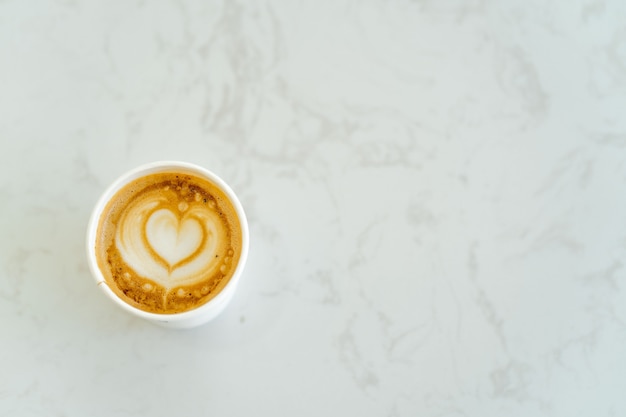 Cup cappuccino with heart shaped pattern on marble table