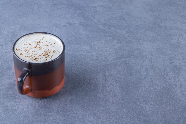 A cup of cappuccino with milk , on the blue background.