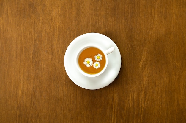 Cup of chamomile tea on wooden background flat lay