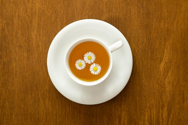 Cup of chamomile tea on wooden background flat lay