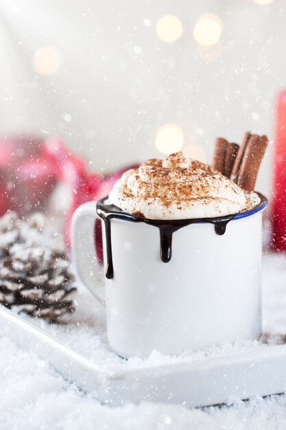 Cup of chocolate with cream and two cinnamon sticks