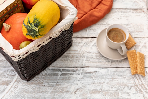 Cup of coffee next to basket with pumpkins