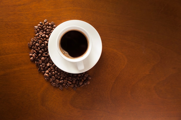 Cup of coffee and beans on wood