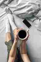 Free photo cup of coffee in bed in female hands top view