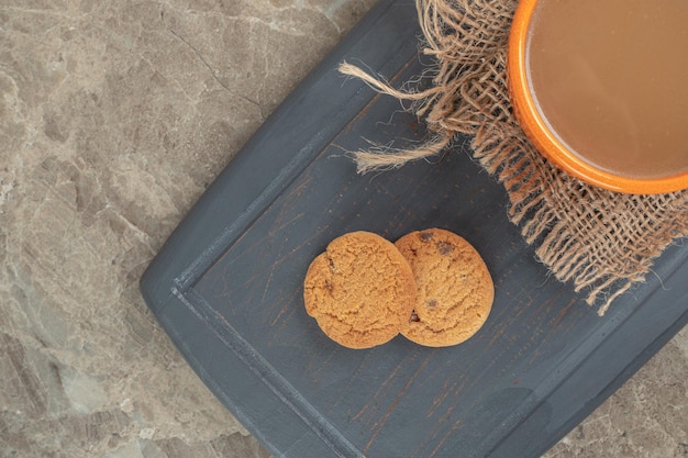 Free photo cup of coffee and biscuits on dark plate.