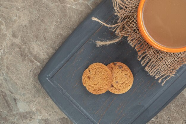 Cup of coffee and biscuits on dark plate. 