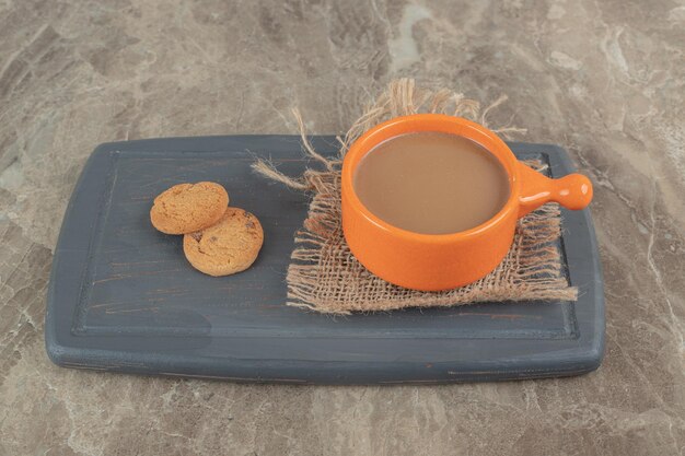Cup of coffee and biscuits on dark plate