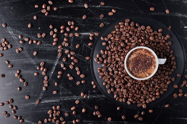 Cup of coffee on brown grains.