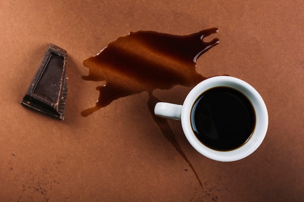 Cup of coffee and chocolate near splash of drink