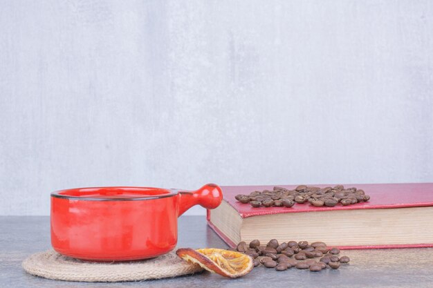 Cup of coffee, coffee beans and book on marble surface. High quality photo