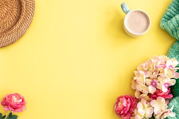 Cup of coffee flowers and knitted element on yellow background flat lay