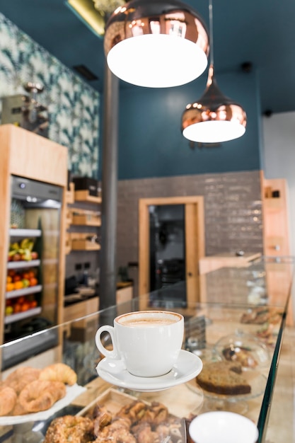 Cup of coffee on glass counter in bakery