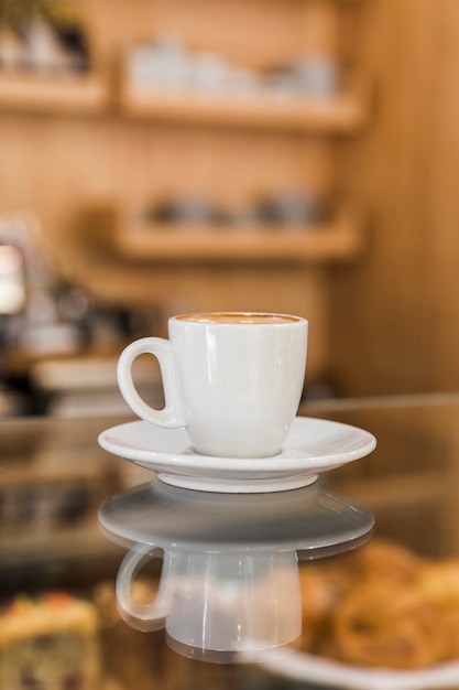 Cup of coffee on glass counter in caf�