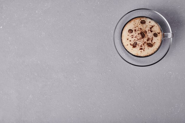 A cup of coffee in glass saucer.