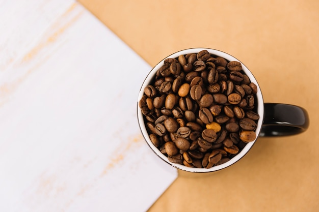Cup of coffee grains near sheet