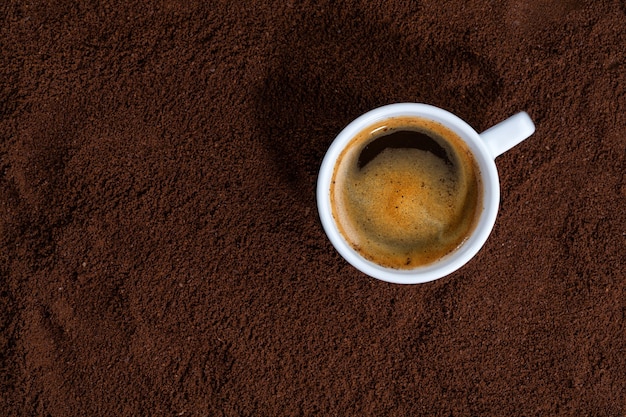 Cup of coffee on ground coffee. Closeup.