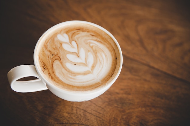 コーヒーショップカフェの木のテーブルにコーヒーのラテカップ