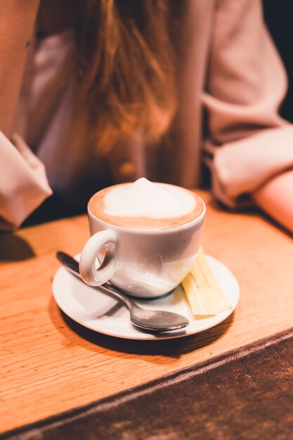 Cup of coffee near crop woman