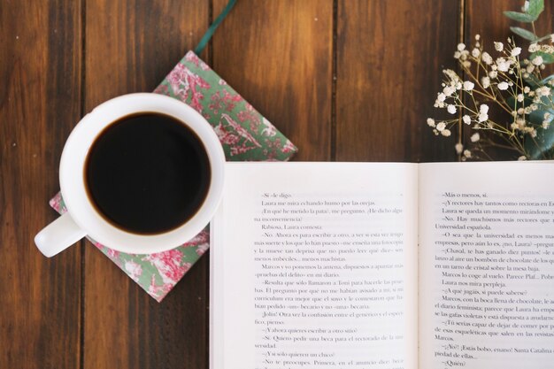 Cup of coffee near opened book