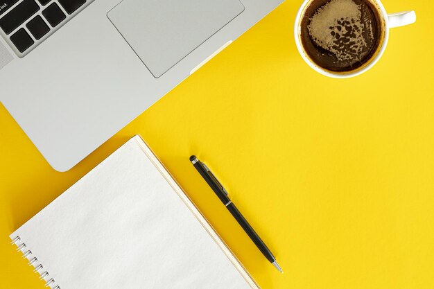 노란색 배경 평면에 커피 노트북과 노트북 컵