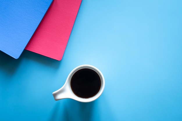 A cup of coffee and notepads on a blue background minimalism