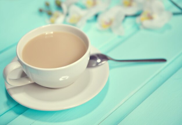 Cup of coffee on old wooden table top view with spring fresh flowers