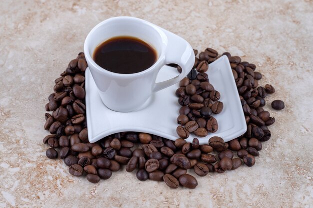 커피 콩 더미에 앉아 접시에 커피 한잔