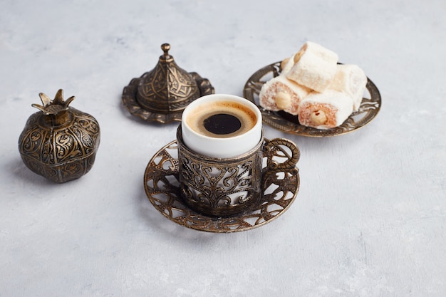 Una tazza di caffè servita con lokum turco sul tavolo bianco.