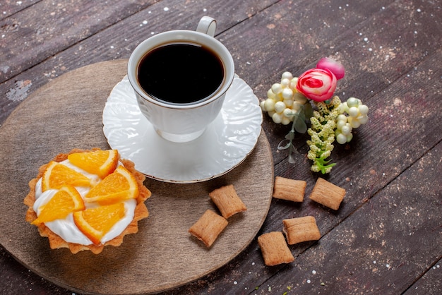 Tazza di caffè forte e caldo insieme a biscotti e torta all'arancia sulla scrivania in legno, frutta cuocere torta al caffè dolce