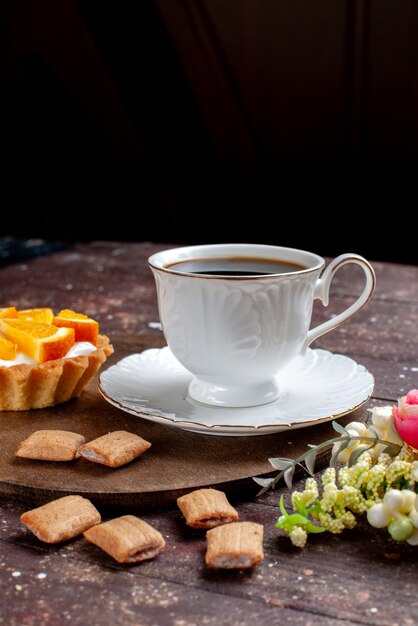 木製の机の上のクッキーとオレンジ色のケーキ、フルーツ焼きコーヒービスケットと一緒に強くて熱いコーヒーのカップ