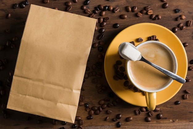 Cup of coffee and sugar near package