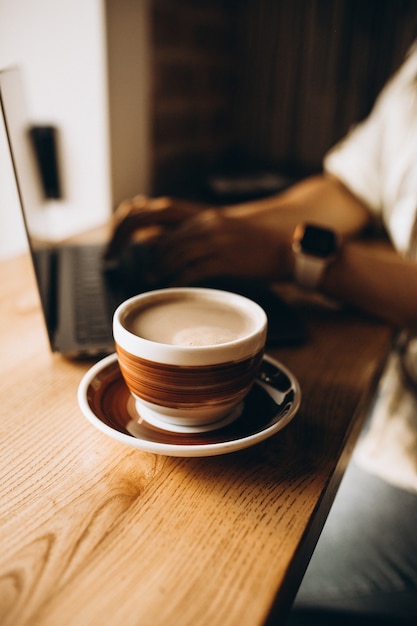 ノートパソコンでテーブルの上のコーヒーカップ