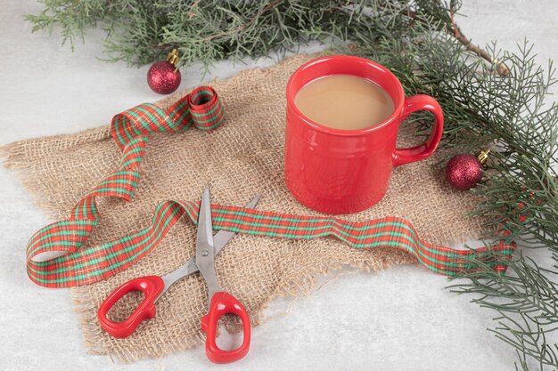 Cup of coffee tied with ribbon on white surface