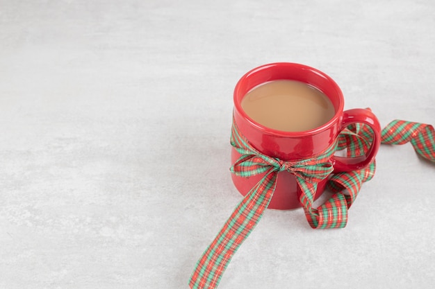 Free photo cup of coffee tied with ribbon on white surface