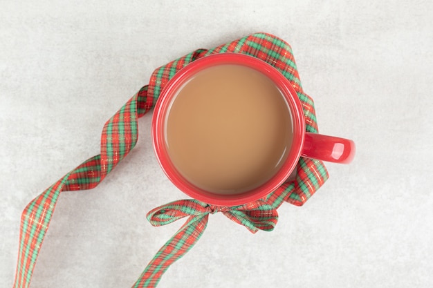 Cup of coffee tied with ribbon on white surface