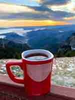 Free photo a cup of coffee on the toaca peak in the carpathians at sunset romania