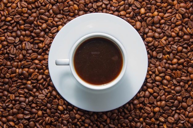 A cup of coffee top view with coffee beans on background