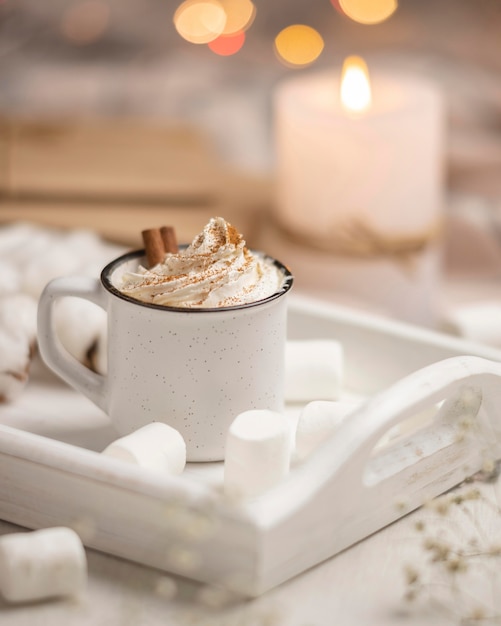 Cup of coffee on tray with marshmallows and candle