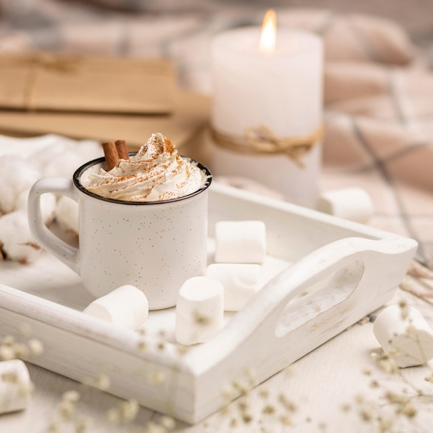 Cup of coffee on tray with whipped cream and candle