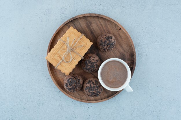 Чашка кофе и различное печенье на деревянной тарелке. Фото высокого качества