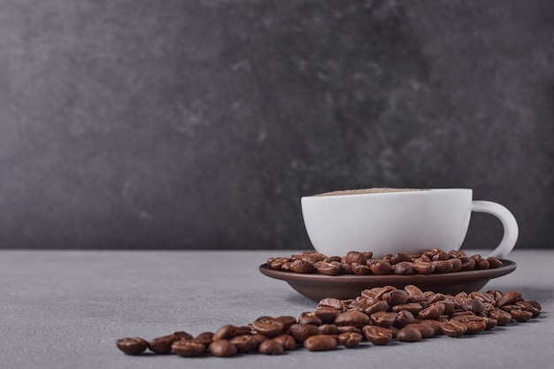 A cup of coffee with arabica beans around.