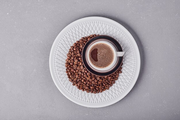 A cup of coffee with arabica beans around.